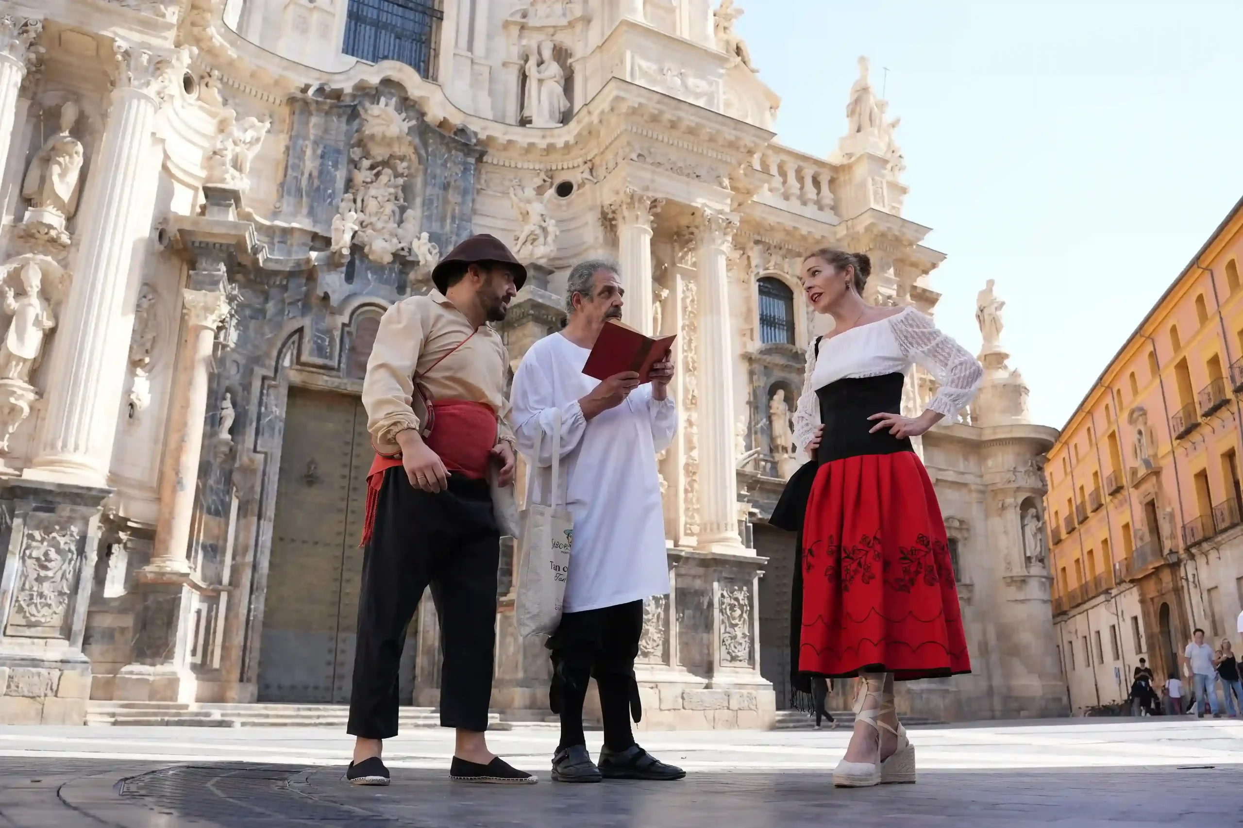 Tres personas interpretando El Quijote junto a la Catedral de Murcia en el evento de Sabor Quijote de Murcia